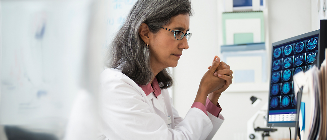 Radiologist reviewing brain MRI images at a diagnostic workstation, from Microsoft's official PowerScribe One product page